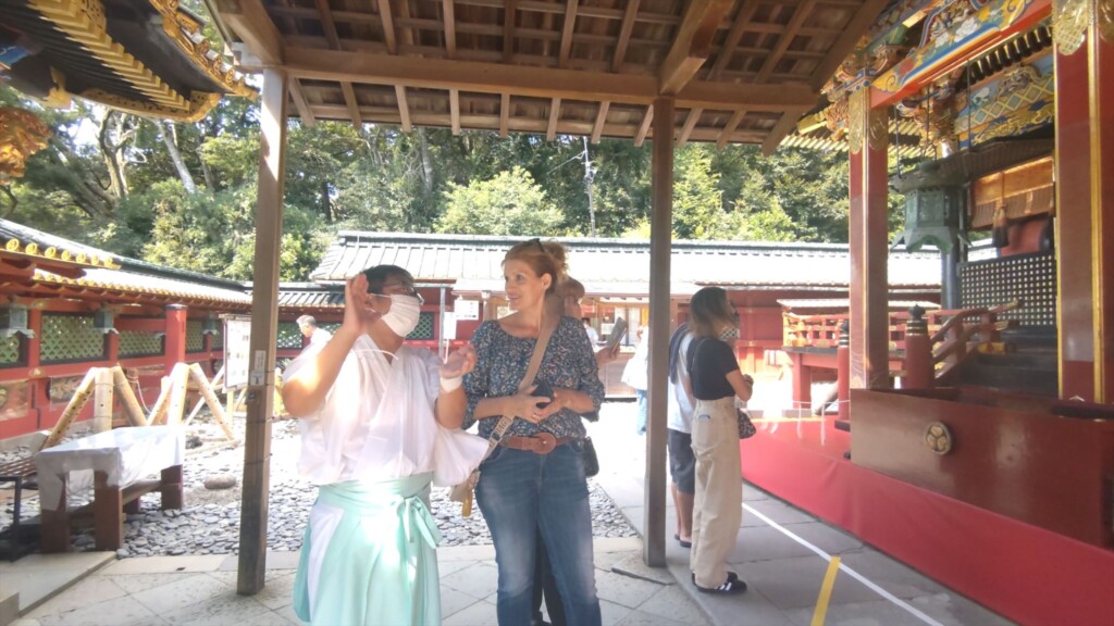 Shinto priest giving a guided tour to foreign tourists in front of the main shrine at Kunozan Toshogu, a historic site in Shizuoka, Japan.