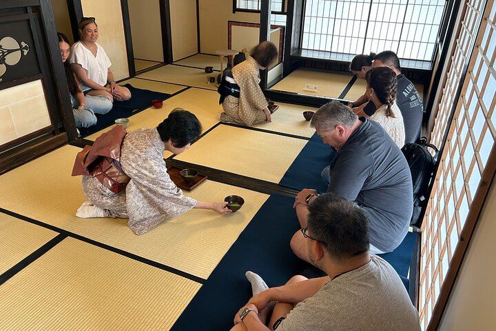 Hawaiian tour group seated facing a tea ceremony instructor in kimono during a cultural experience in Shimada, Japan.